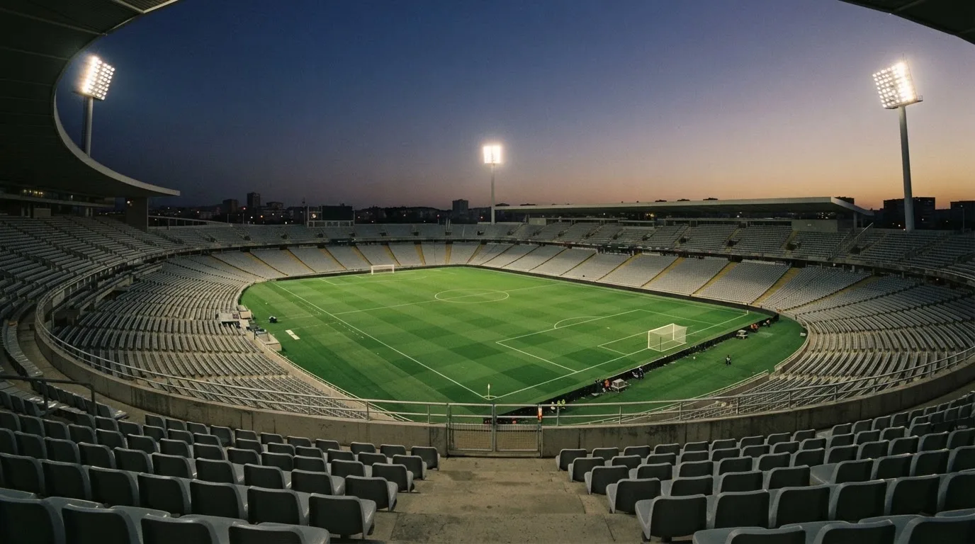 Een leeg voetbalstadion met lichtmasten bij schemering
