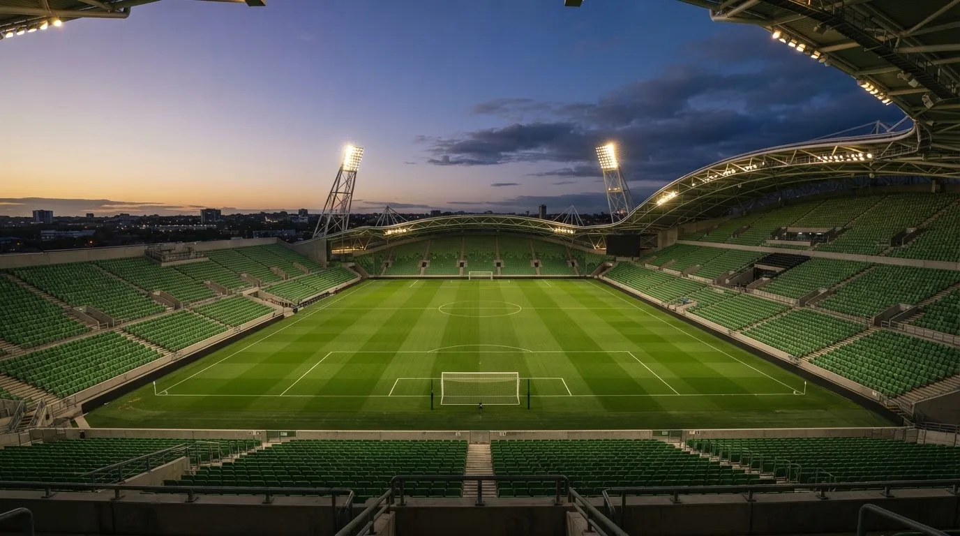 Een leeg voetbalstadion met lichtmasten bij schemering