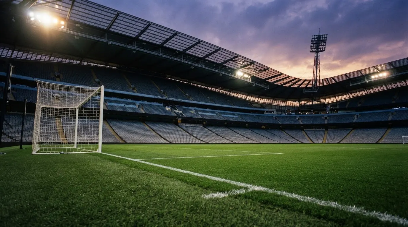 Een leeg voetbalstadion met lichtmasten bij schemering