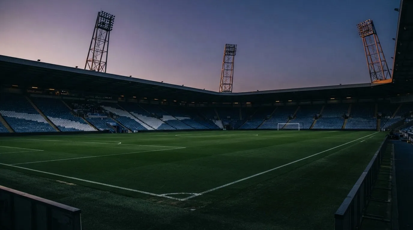 Een leeg voetbalstadion met lichtmasten bij schemering