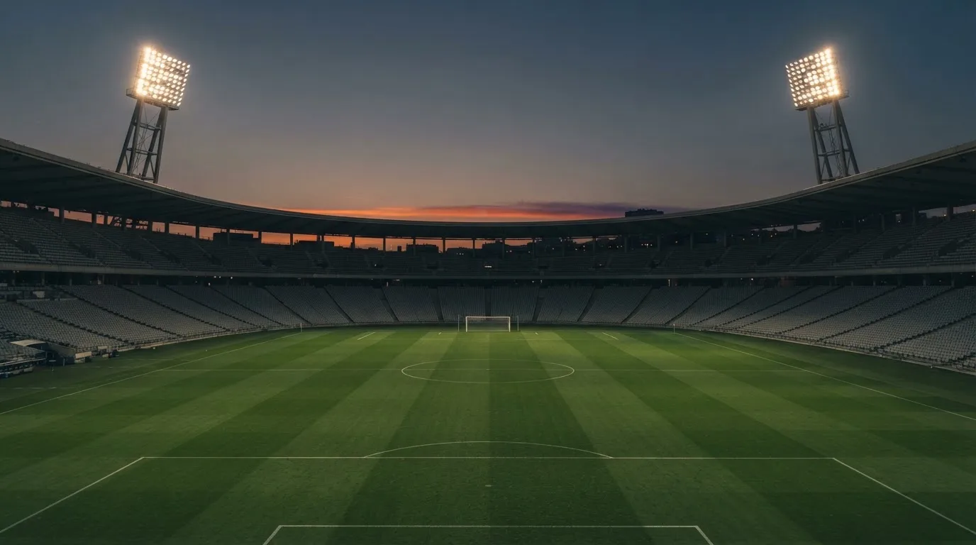Een leeg voetbalstadion met lichtmasten bij schemering
