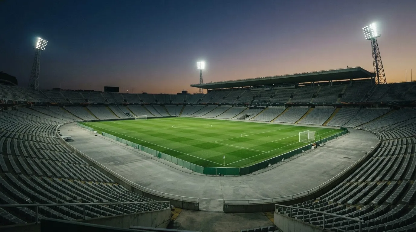 Een leeg voetbalstadion met lichtmasten bij schemering