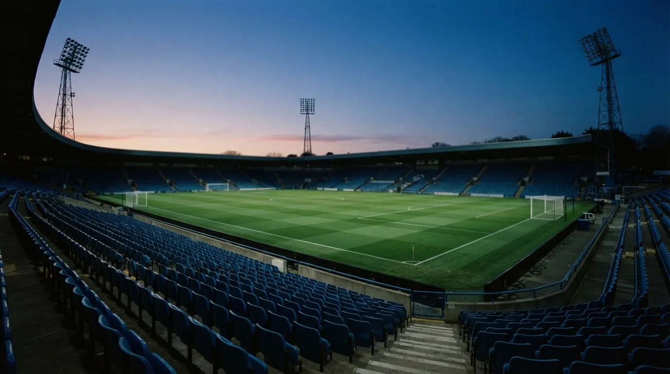 Een leeg voetbalstadion met lichtmasten bij schemering