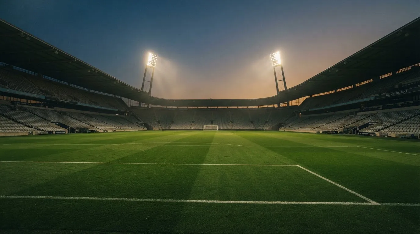 Een leeg voetbalstadion met lichtmasten bij schemering