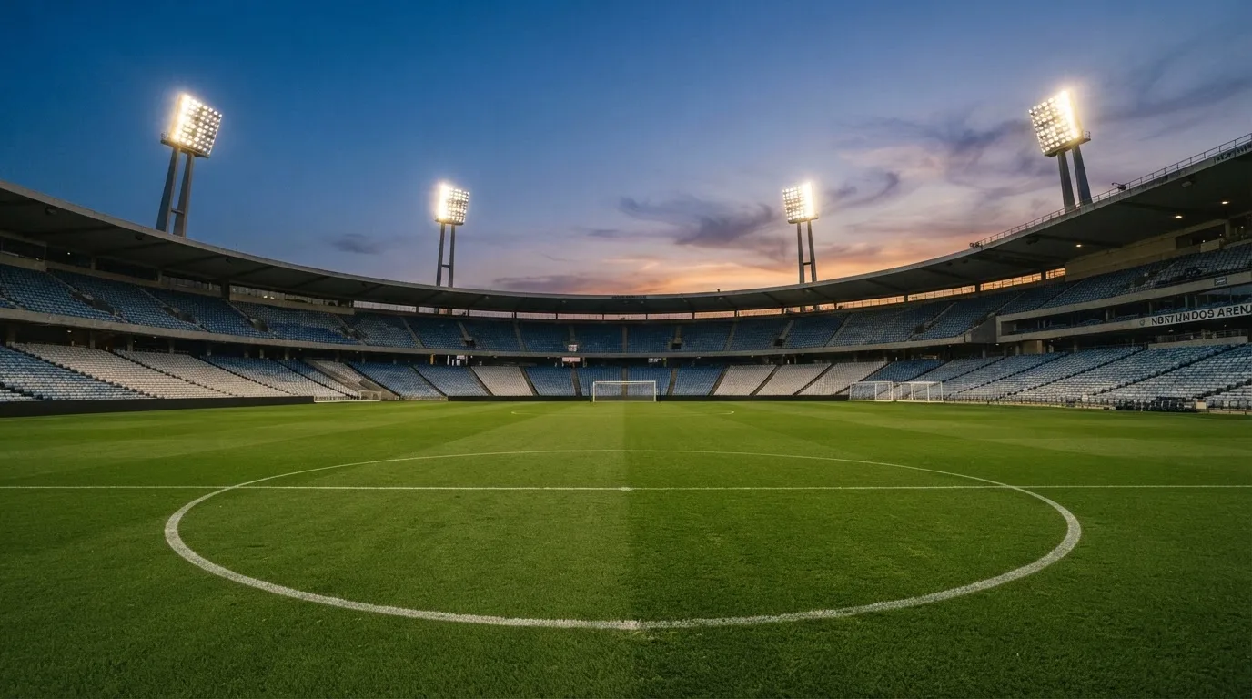 Een leeg voetbalstadion met lichtmasten bij schemering