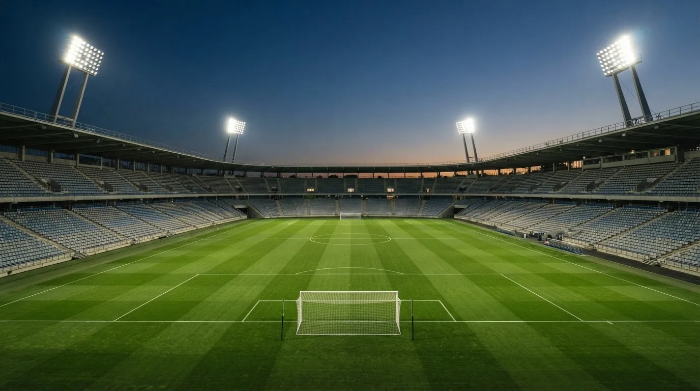 Een leeg voetbalstadion met lichtmasten bij schemering