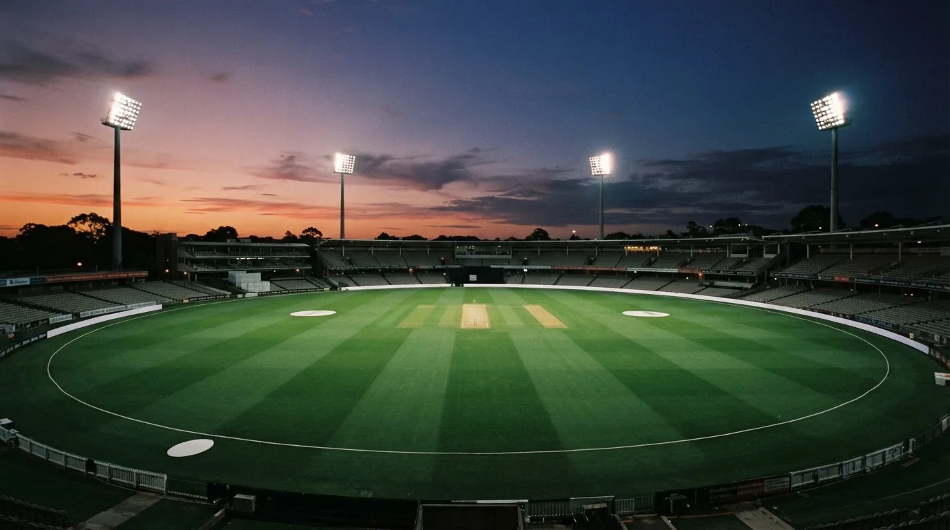 Een leeg voetbalstadion met lichtmasten bij schemering