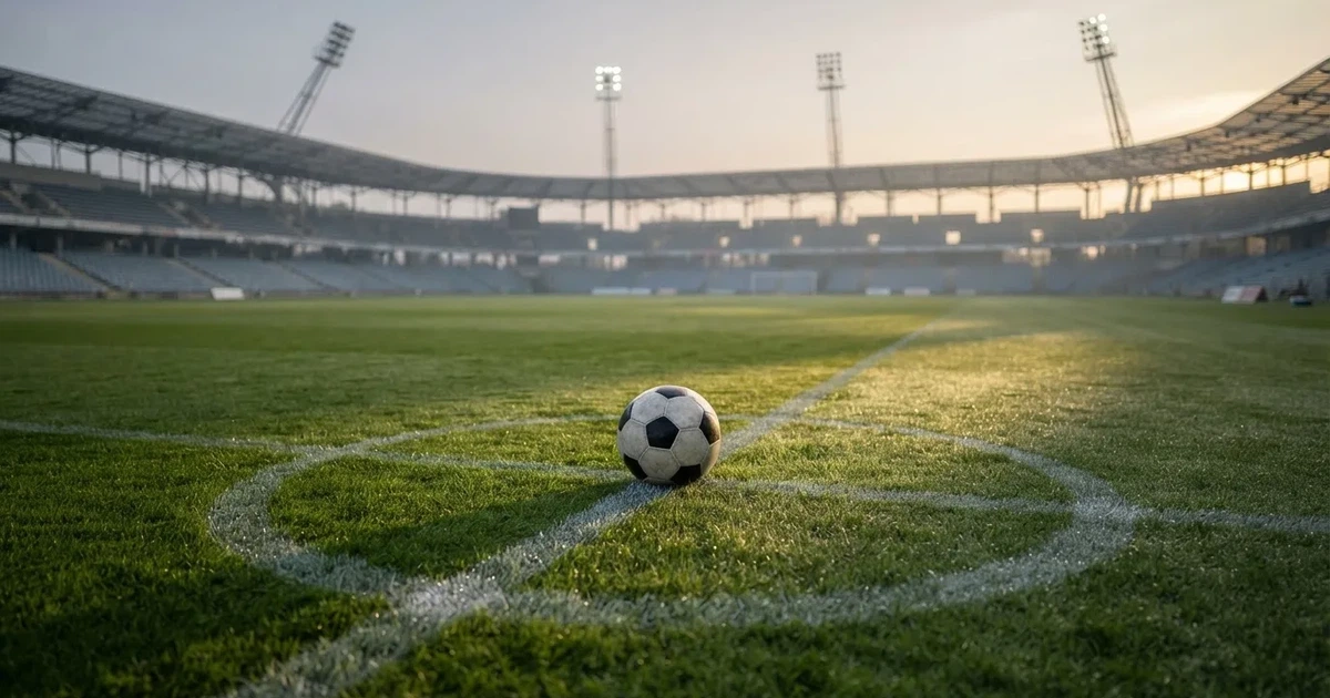 Een voetbal op de middenstip van een grasveld in het ochtendlicht